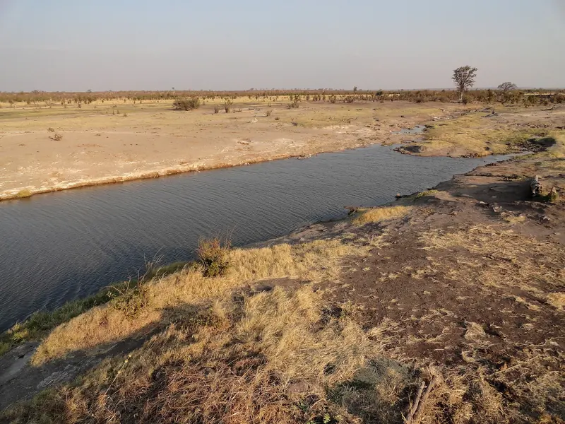 A waterhole stretching across dry grassland in Hwange National Park
